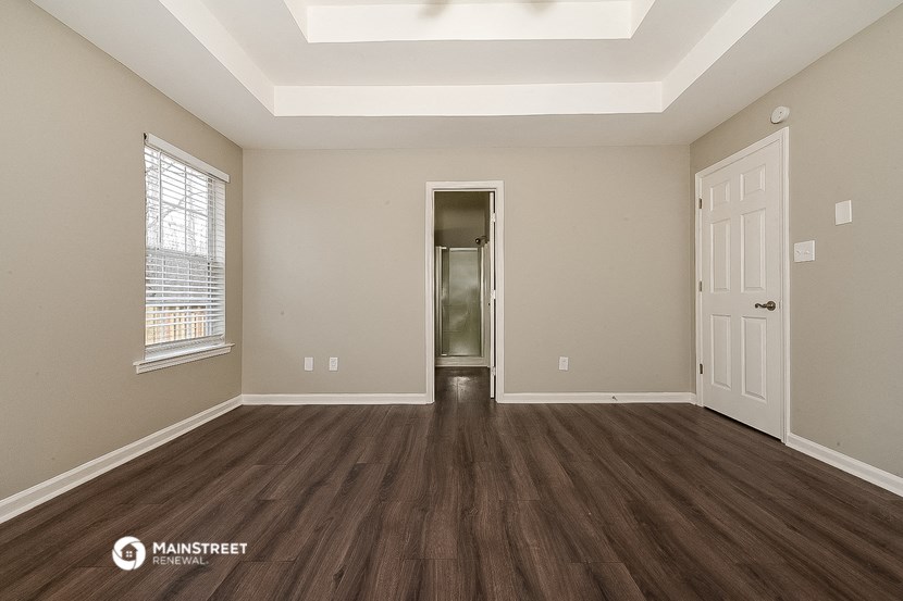 the spacious living room with hardwood flooring and an open door to the bathroom