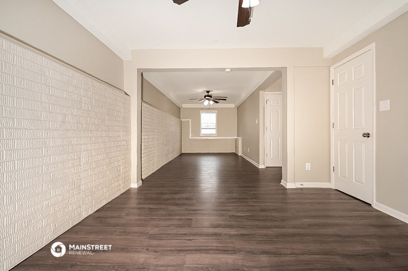 an empty living room with wood floors and a ceiling fan