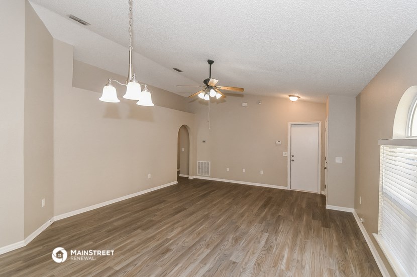 the spacious living room and dining room with hardwood flooring and a ceiling fan
