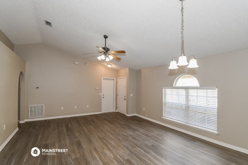 an empty living room with a ceiling fan and a window