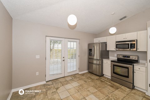 the kitchen has stainless steel appliances and white cabinets