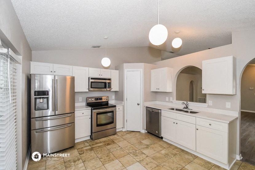 the kitchen has stainless steel appliances and white cabinets