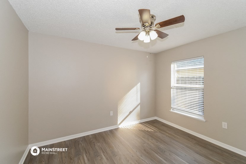 the spacious living room with ceiling fan and wood flooring