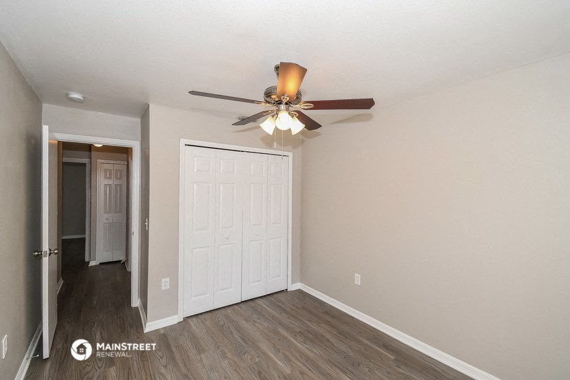 a bedroom with a ceiling fan and a door to a closet