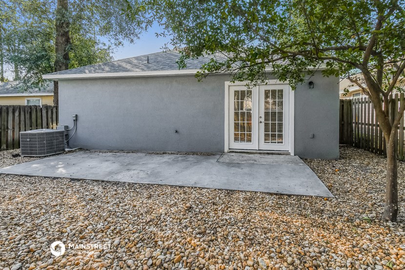 a small white house with a driveway and a tree