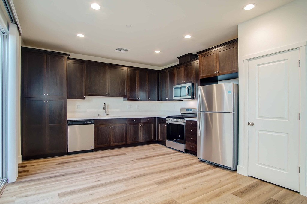 a kitchen with dark wood cabinets and stainless steel appliances