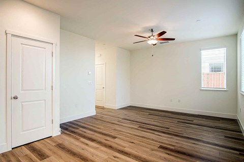 an empty living room with white walls and a ceiling fan