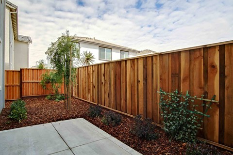 a wooden fence in a yard with a house behind it