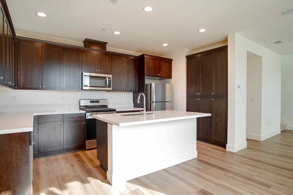 a kitchen with a large white island and dark wood cabinets
