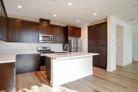 a kitchen with a large white island and dark wood cabinets