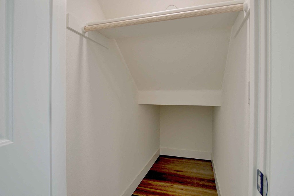 a small closet in a room with white walls and a wood floor