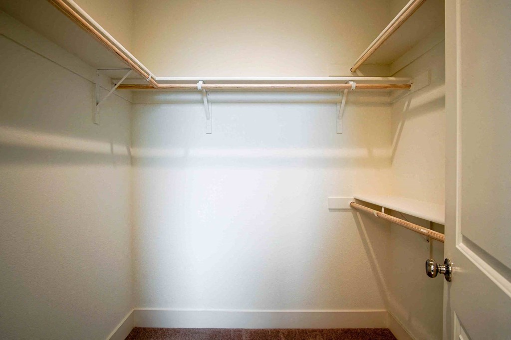 a walk in closet in an empty room with a white wall