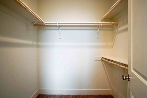 a walk in closet in an empty room with a white wall