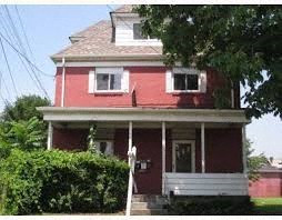 a red house with a white porch and a tree