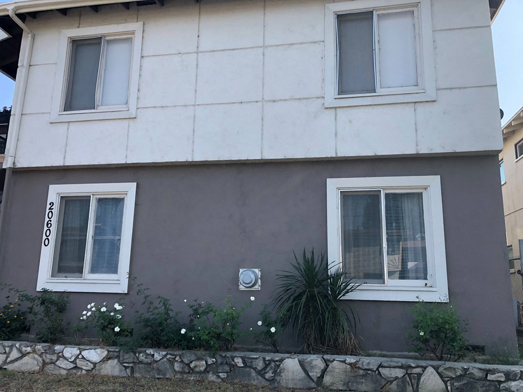 a house with two windows and a wall with flowers in front of it