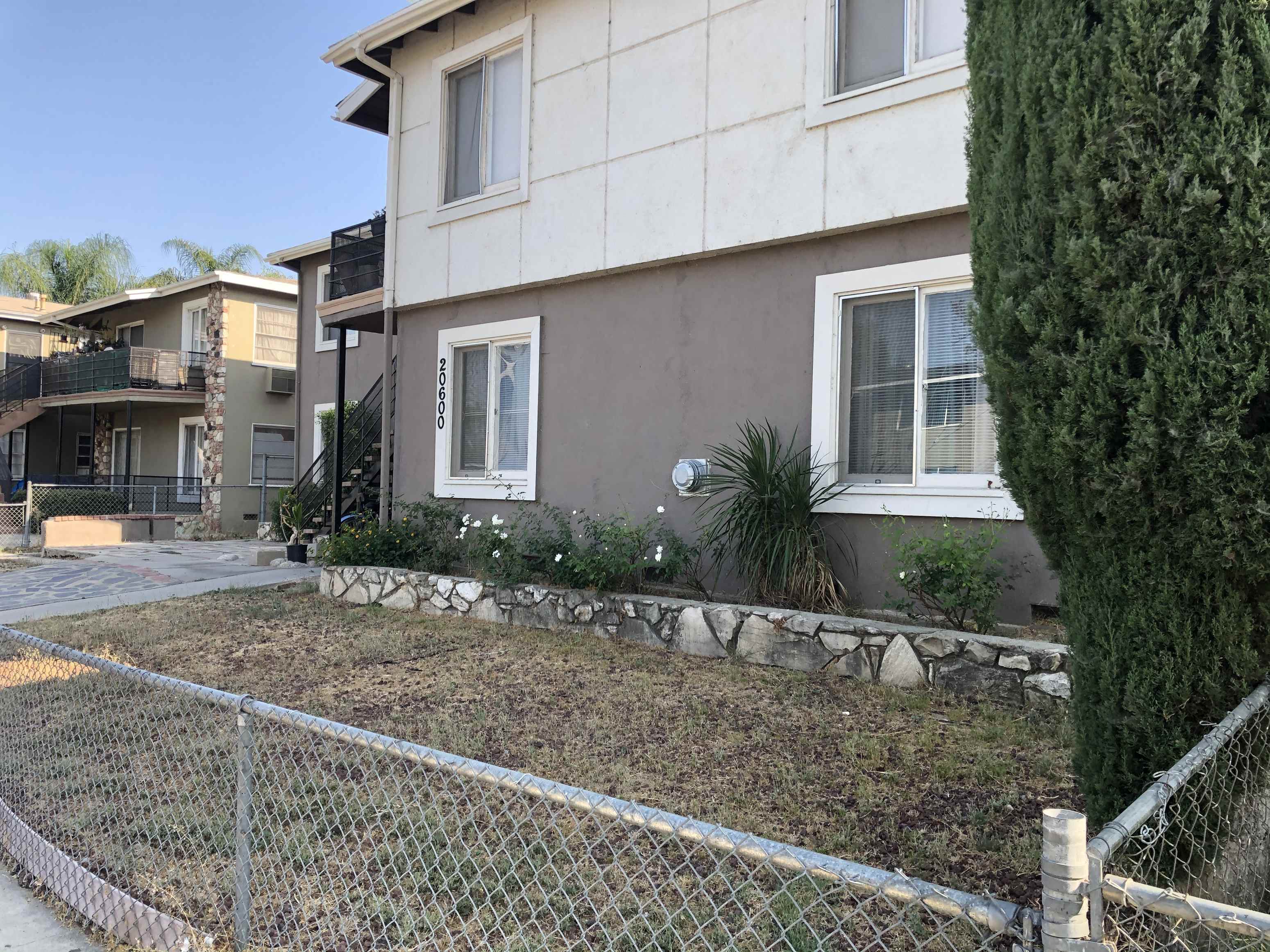 a house with a yard behind a chain link fence