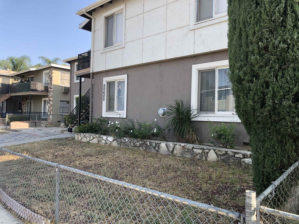 a house with a yard behind a chain link fence