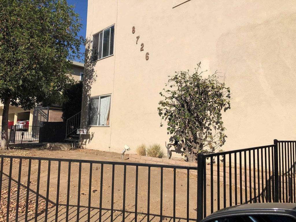 A black fence in front of a beige building with the number 726 on it.