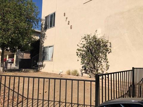 A black fence in front of a beige building with the number 726 on it.