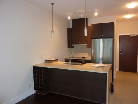 A kitchen with a refrigerator, sink, and cabinets.