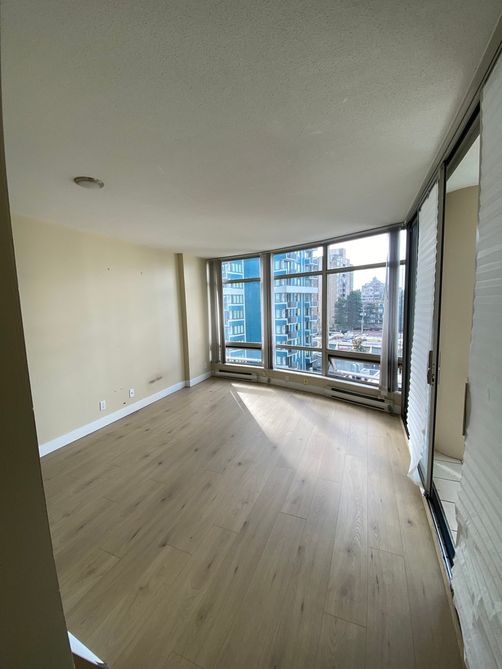 A room with wooden floors and a large window overlooking a city.