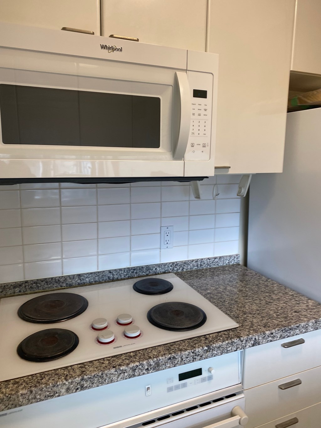 A white microwave oven is mounted above a stove top.