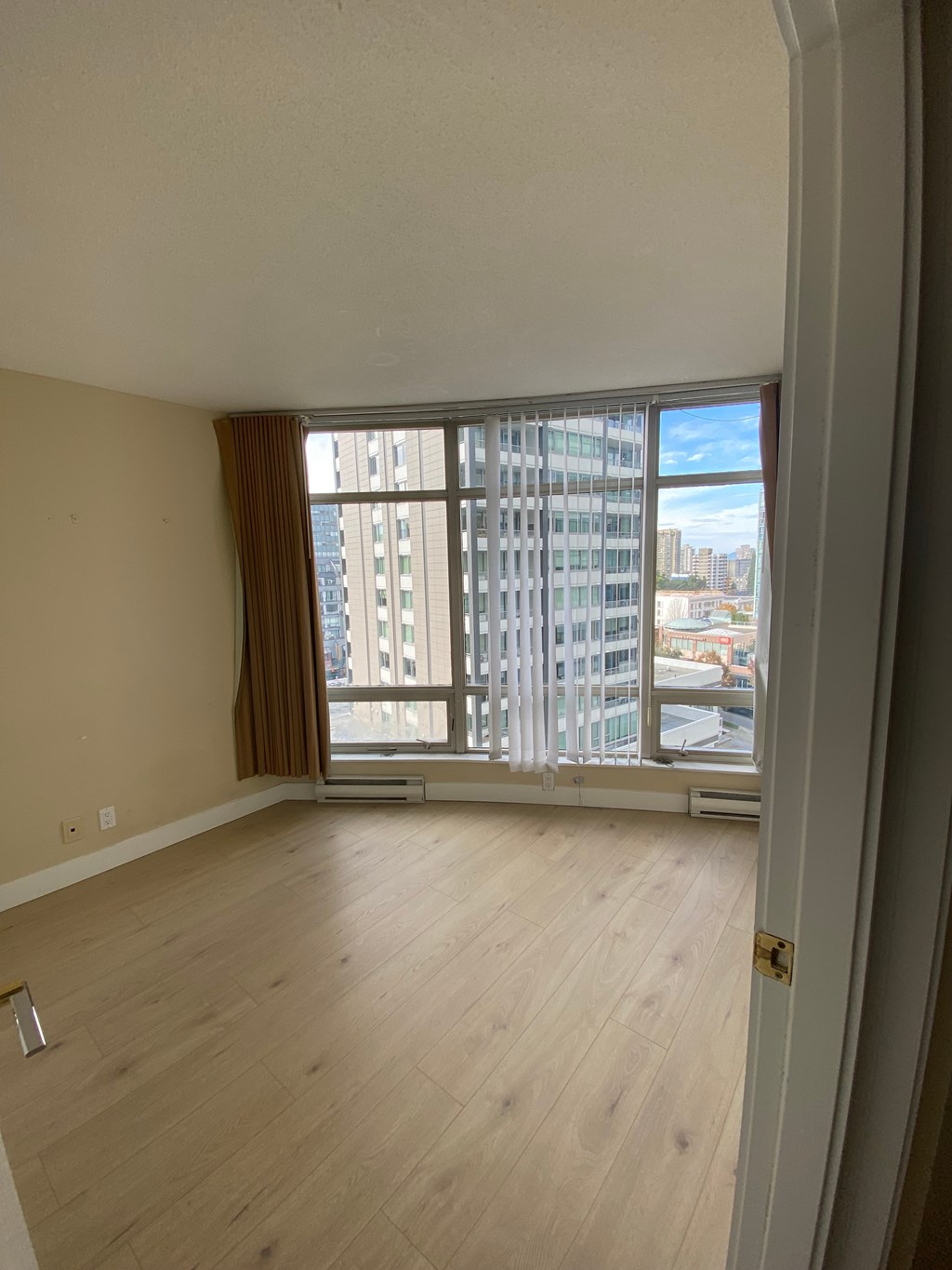 A room with a large window and wooden flooring.