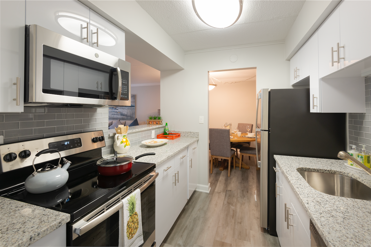 a kitchen with white cabinets and granite counter tops and a stainless steel refrigerator and microwave