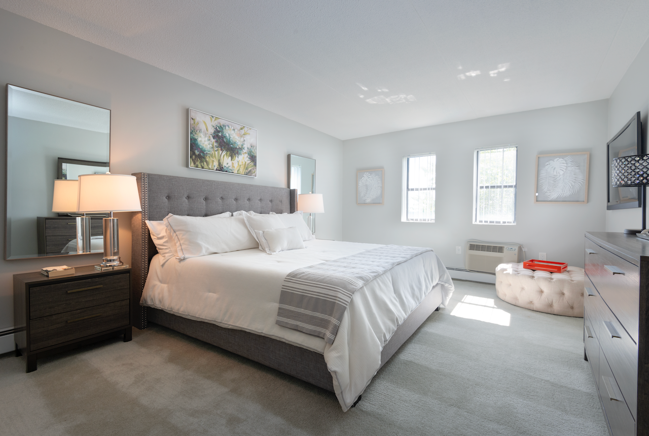 a bedroom with a bed and a dresser and a mirror