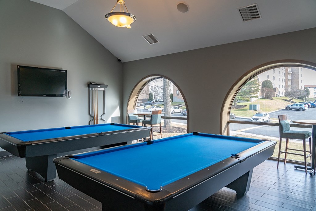 two pool tables in a game room with a tv