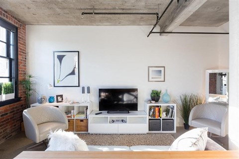 A living room with a white couch, a television, and a fireplace.