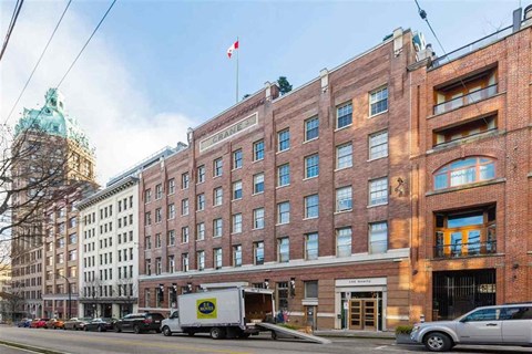 A street view of a city with a building that has a Canadian flag on top.