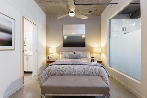 A bedroom with a bed, two lamps, and a ceiling fan.