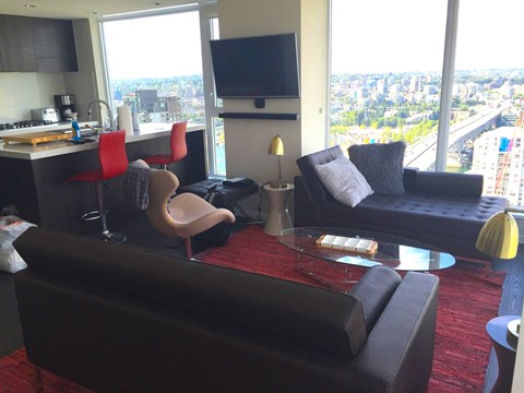A living room with a red carpet and a large window overlooking a city.
