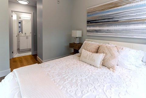 a bedroom with a white bed and a painting on the wall