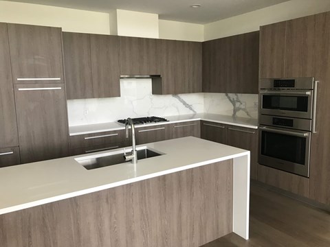 A modern kitchen with a white countertop and stainless steel appliances.