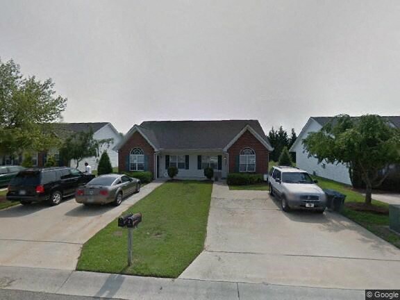 A house with a driveway and cars parked in front.