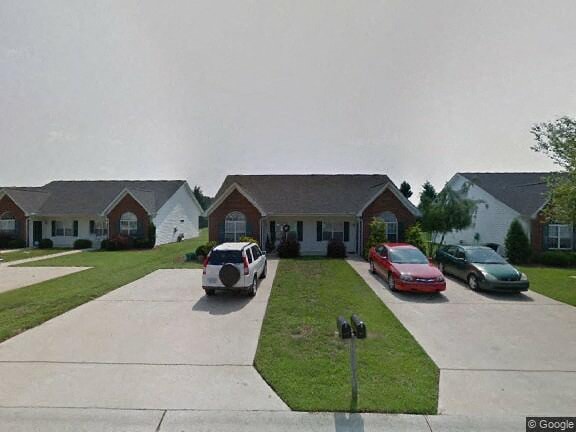 A white car is parked in front of a house.