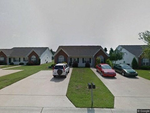 A white car is parked in front of a house.