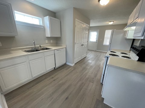A kitchen with white cabinets and a wooden floor.