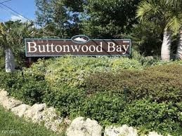 a sign forbuttwood bay in front of some bushes and trees