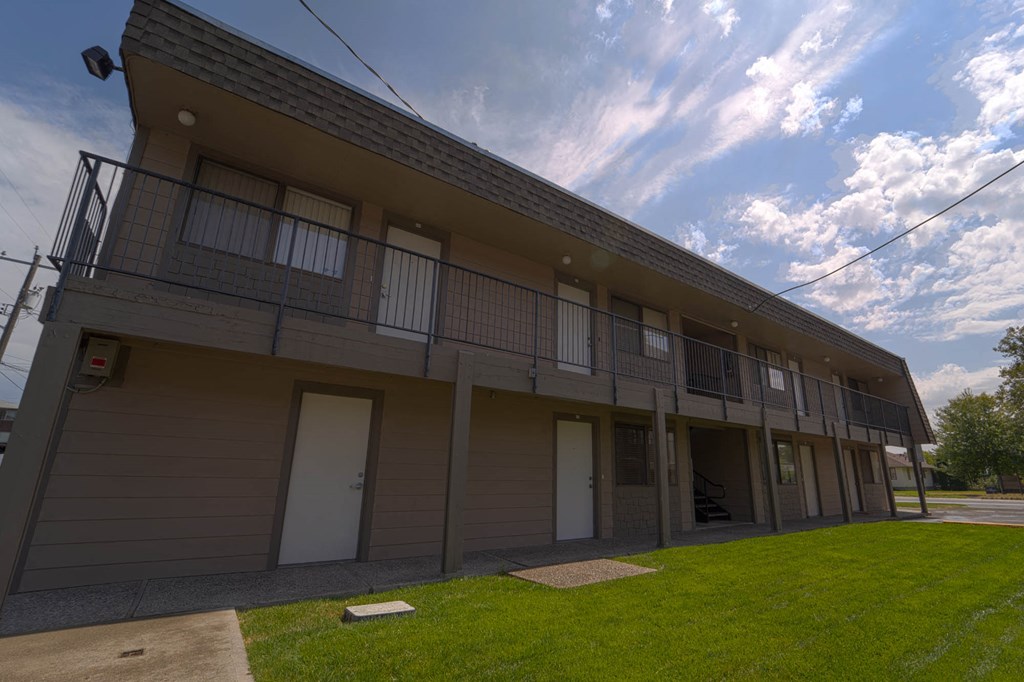 the front of a tan building with a green lawn