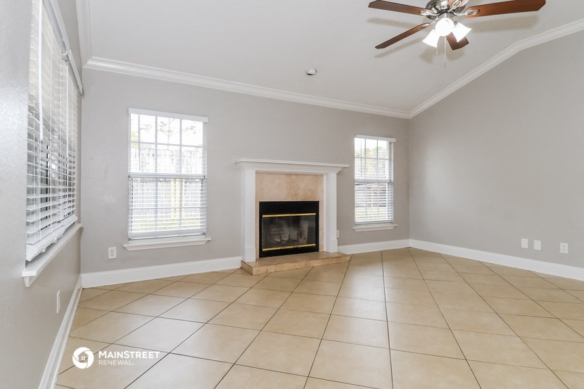 an empty living room with a fireplace and a ceiling fan