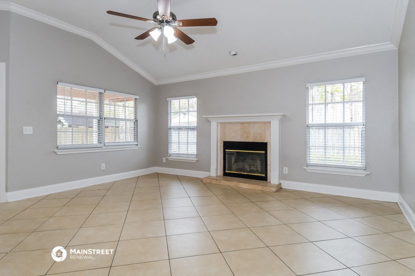 an empty living room with a fireplace and a ceiling fan