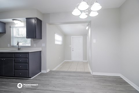 a renovated kitchen with black cabinets and white walls and a white door