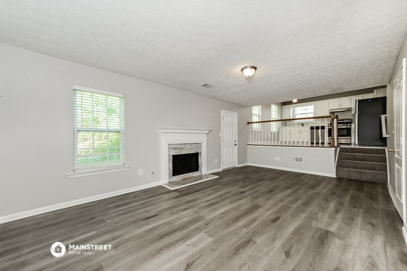 the living room is spacious and has a fireplace and hardwood flooring