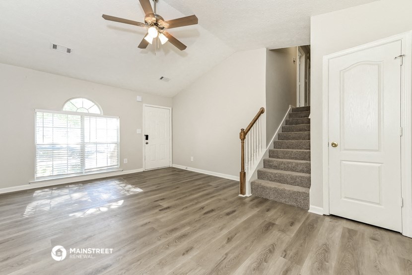 the living room and entryway of an empty house with a ceiling fan
