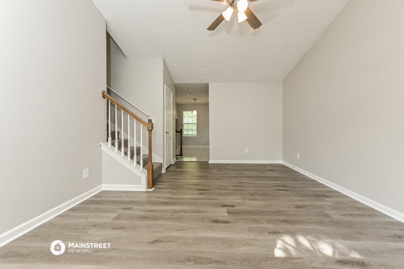 the spacious living room is empty and has a ceiling fan