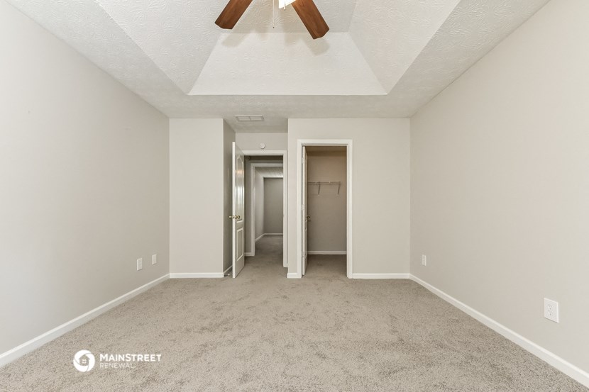 a spacious living room with carpet and a ceiling fan