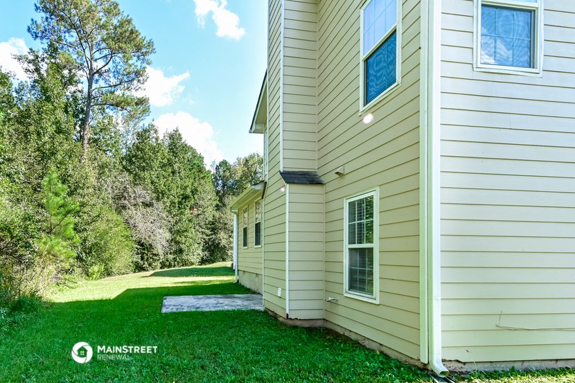 the side of a house with a yard and trees